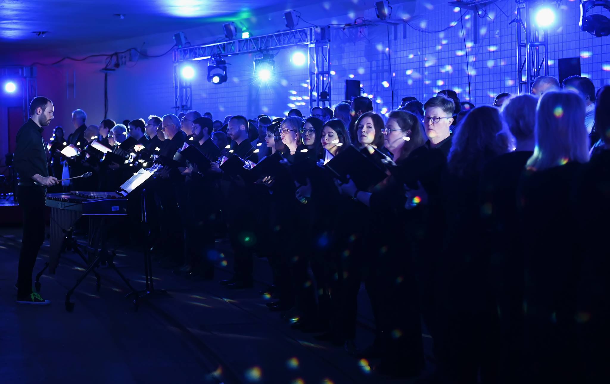 A choir performing on the platform under blue light